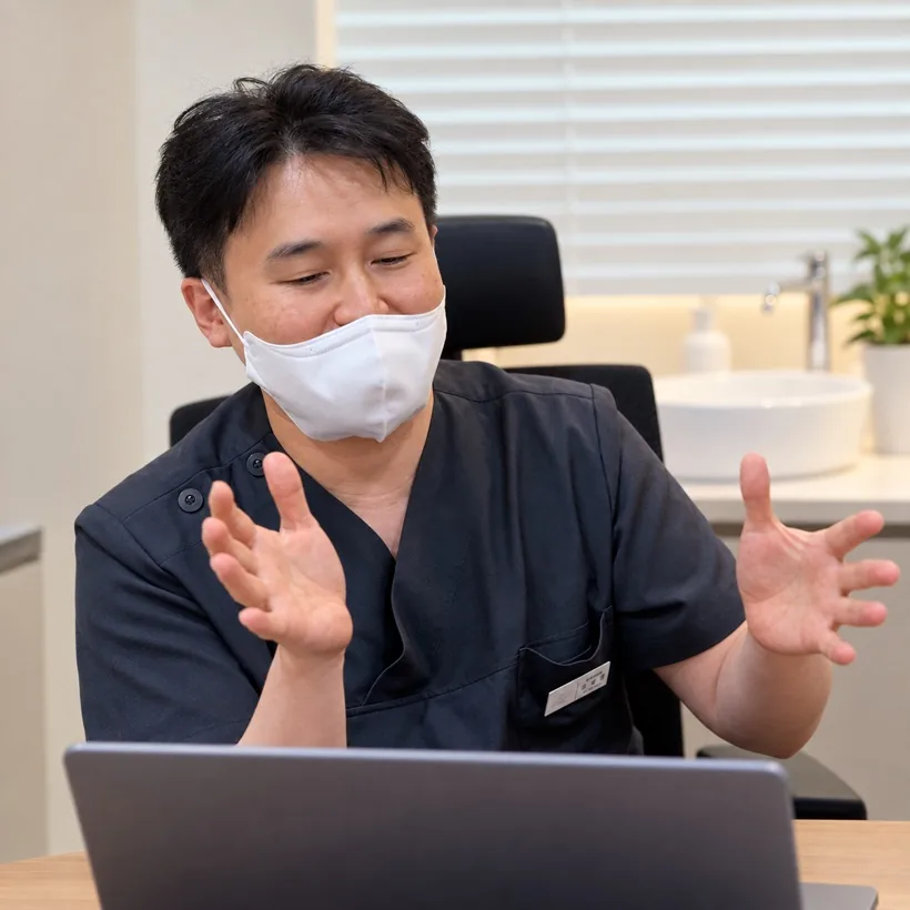 A doctor in a mask talking with IO at a desk